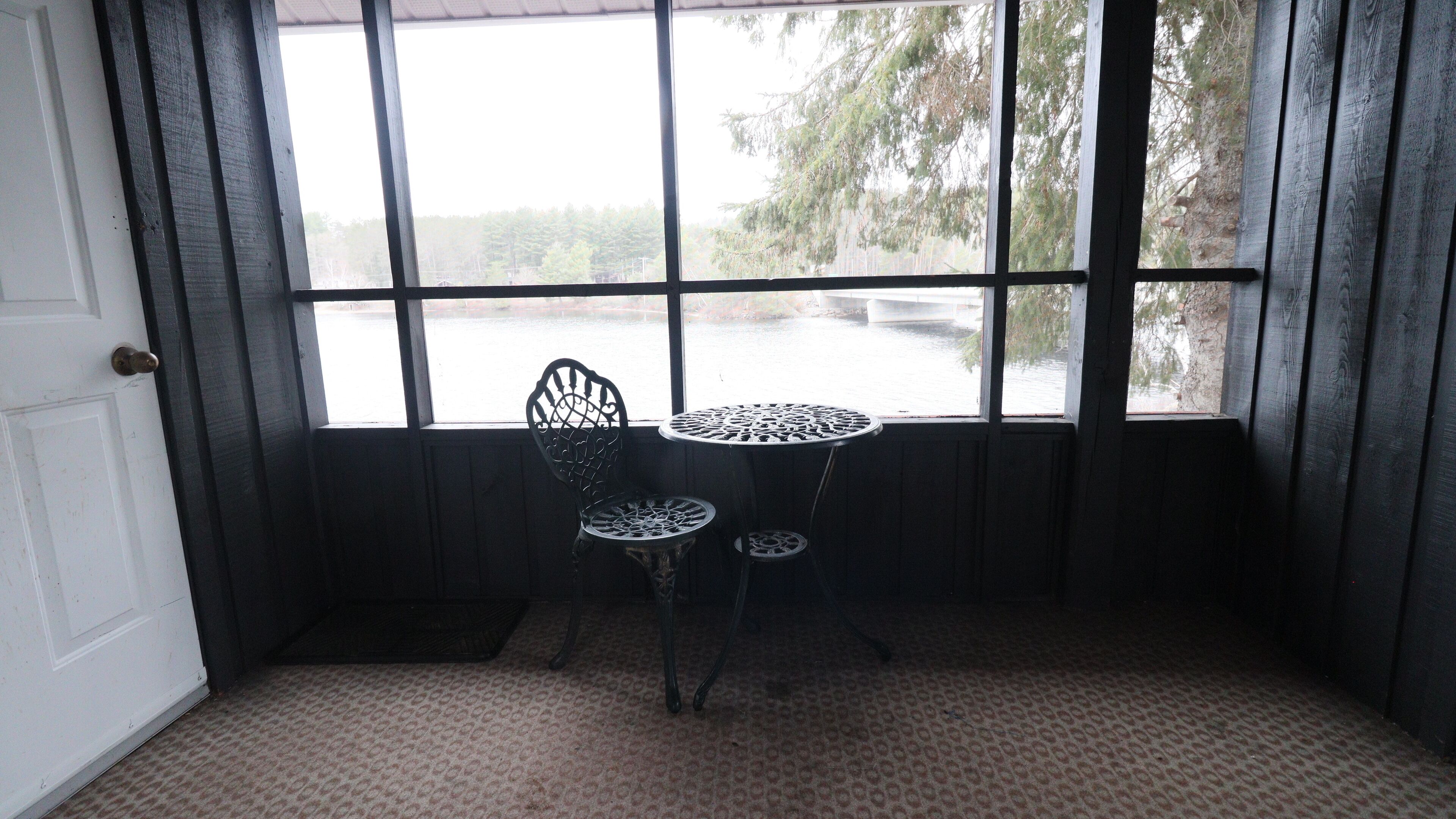 A room with a window, a door, and a small table with two chairs.