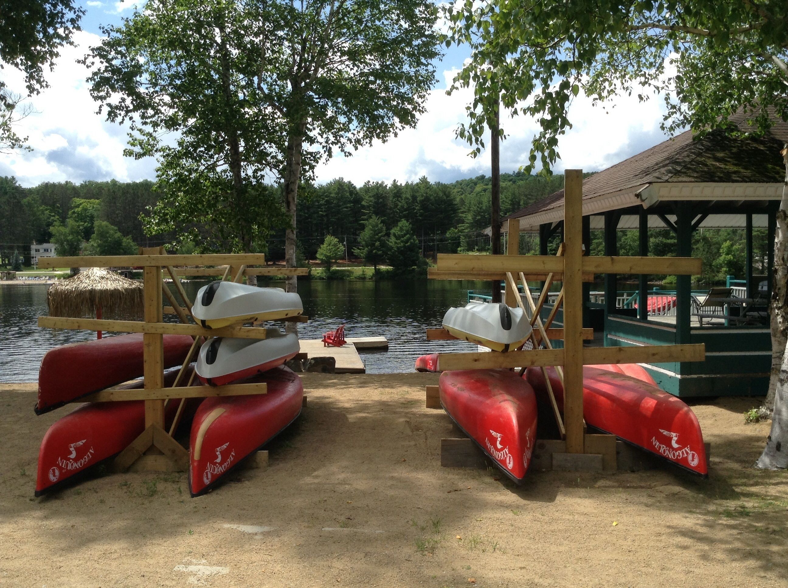 Un muelle en la orilla del lago con canoas y kayaks.