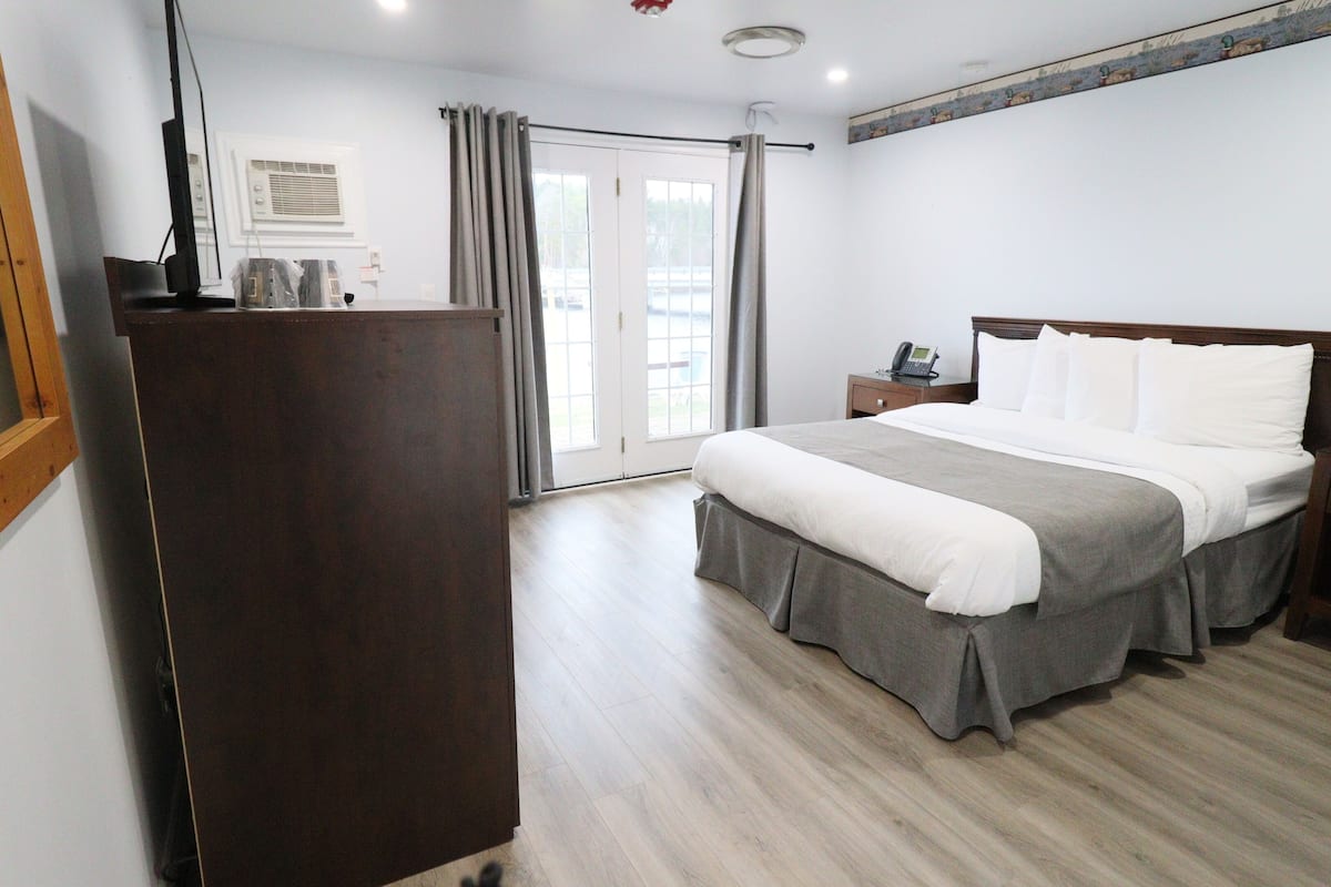 Une chambre d’hôtel comprenant un lit, une table de chevet et un bureau avec un téléphone.
