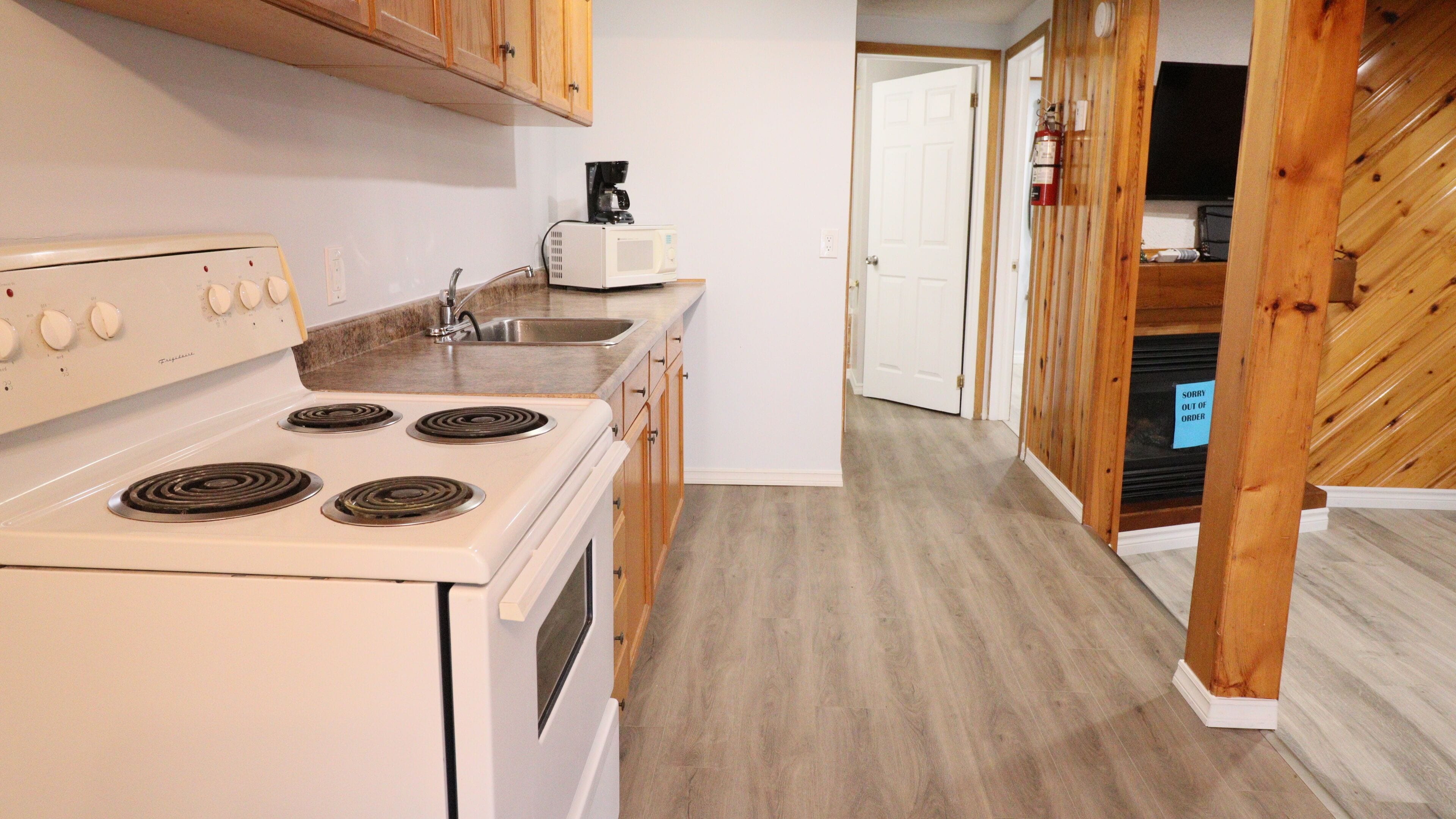 A compact kitchen with a stove, microwave, and sink.