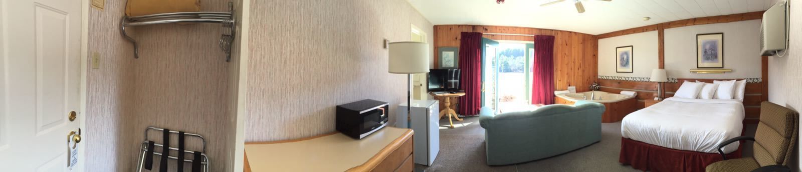 A hotel room with a bed, a sofa, a TV, a desk, and a bathroom.