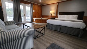 A hotel room with a bed, a sofa, a small table, a bathtub, and a window with curtains.