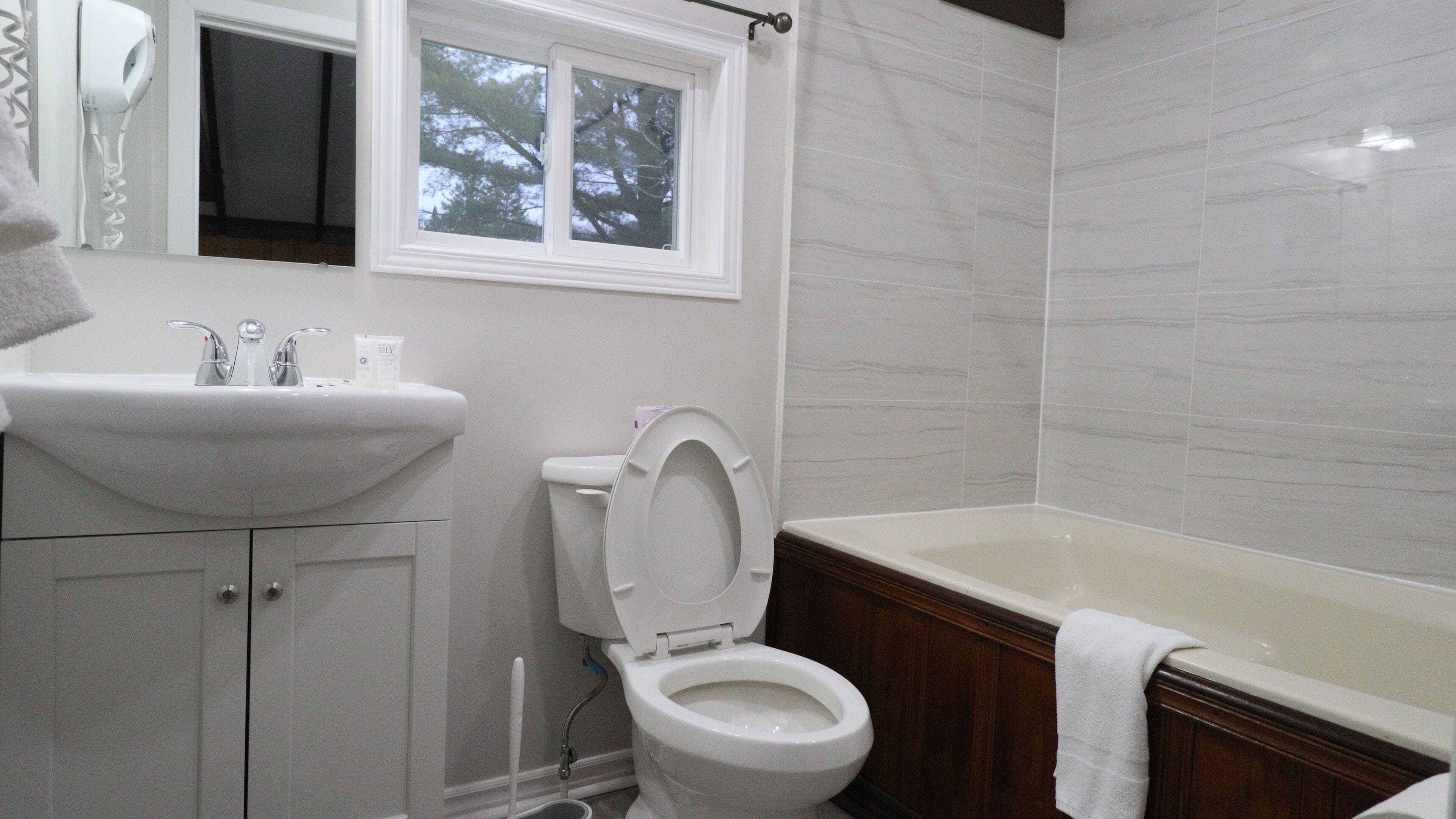 Un bagno con lavandino, water e vasca da bagno bianchi.