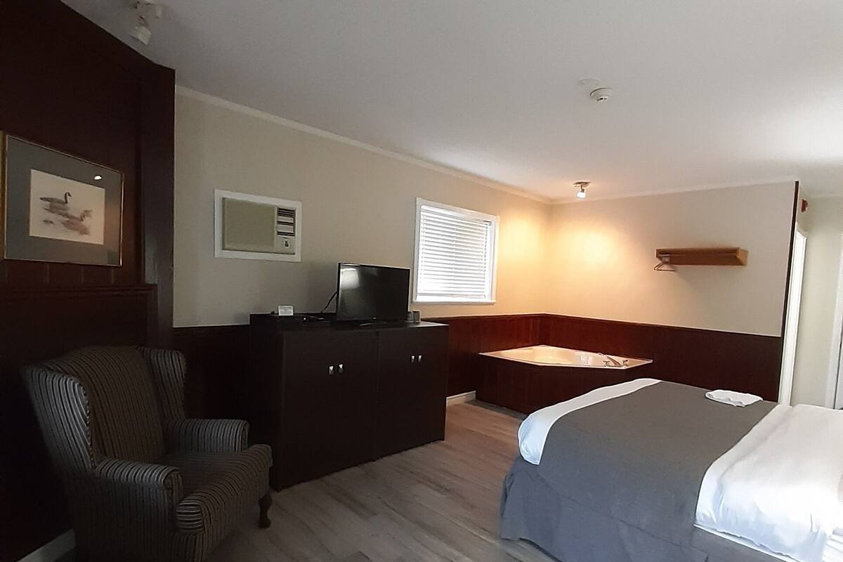 Une chambre d’hôtel avec un lit, un bureau, une chaise et un téléviseur.