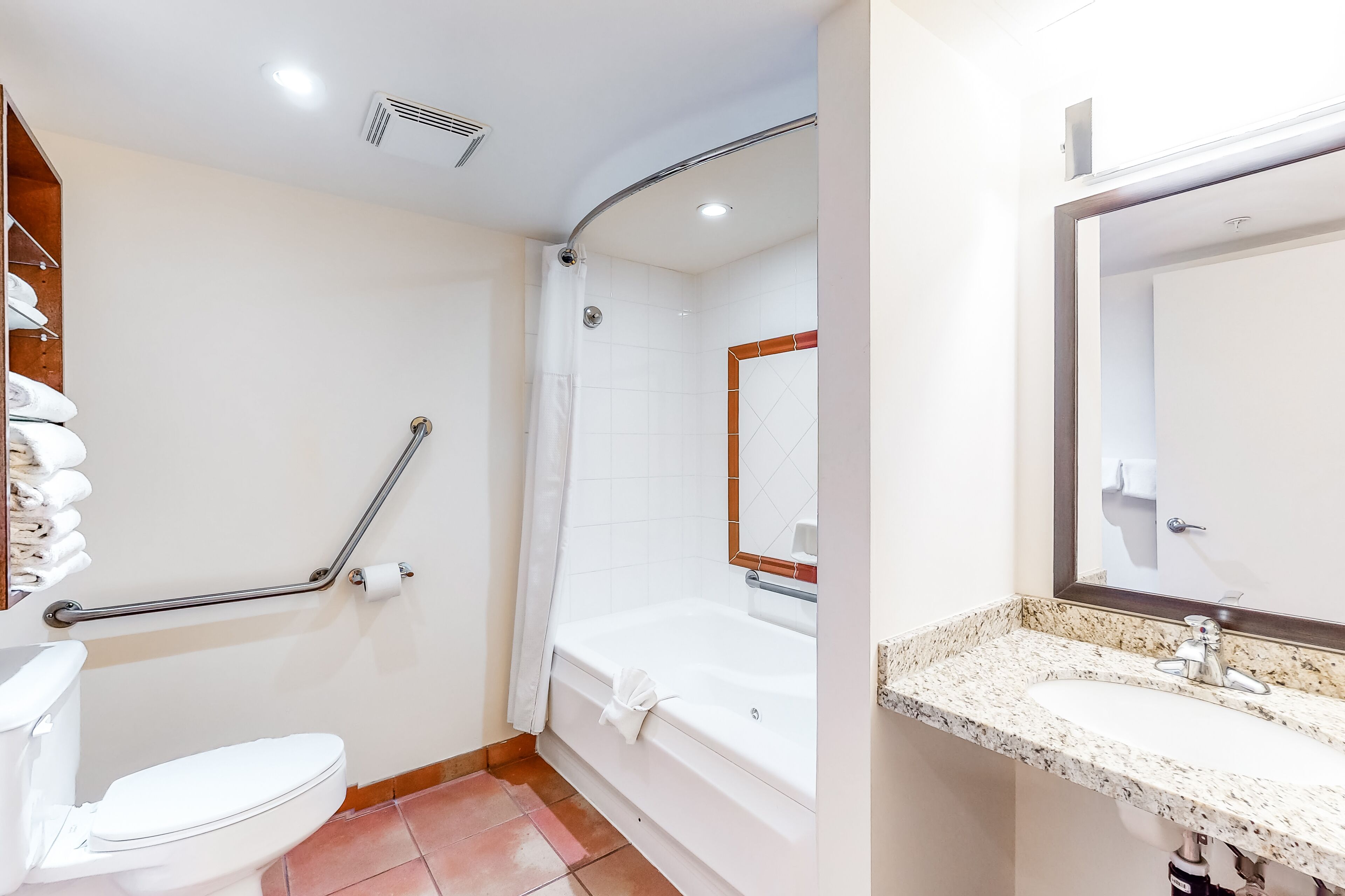 A bathroom with a white toilet, a shower with a grab bar, a bathtub, and a sink with a mirror.