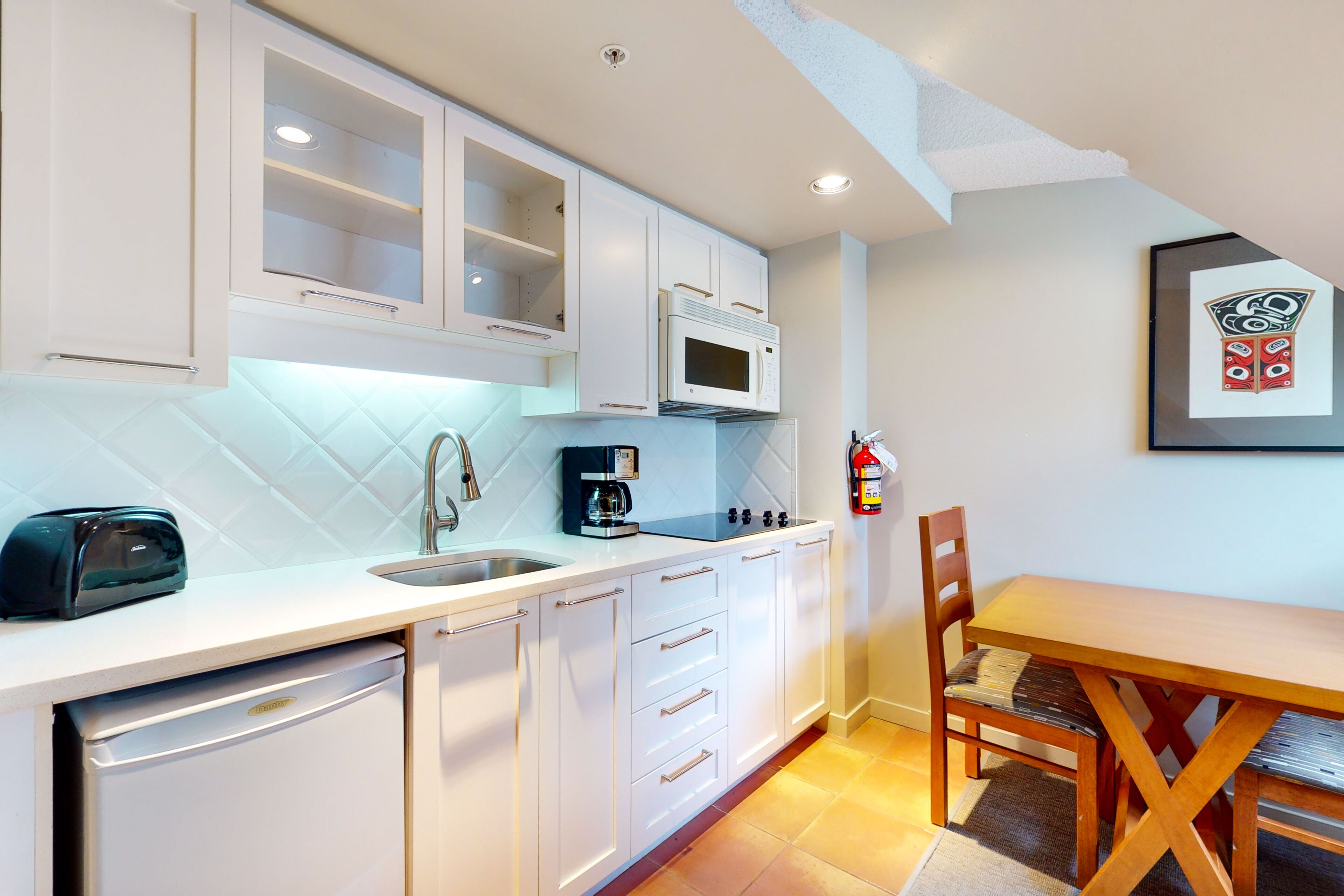 A kitchen with white cabinets, a microwave, a coffee maker, and a dishwasher.