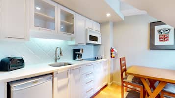 A kitchen with white cabinets, a microwave, a coffee maker, and a dishwasher.