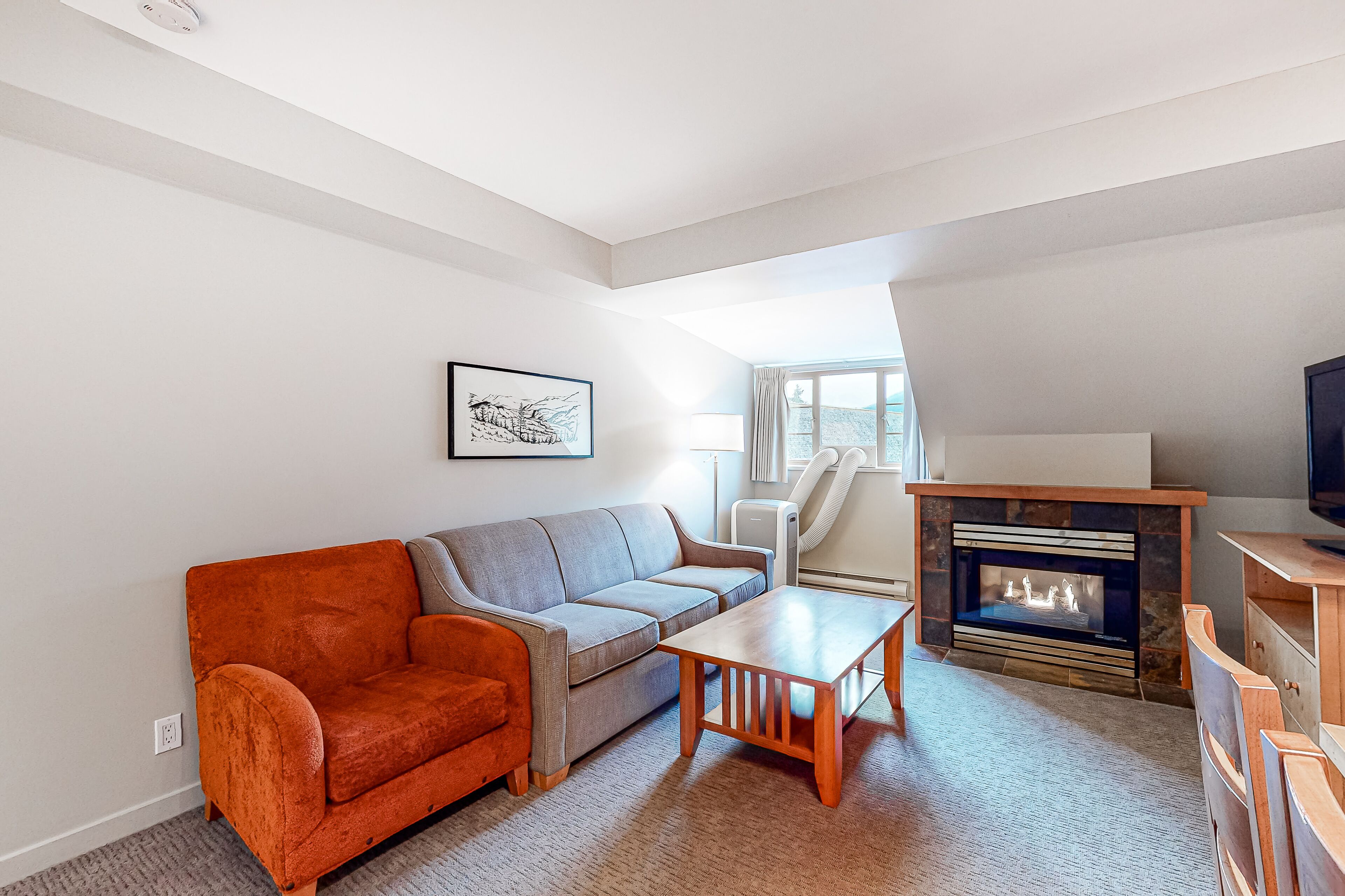 A living room with a sofa, a coffee table, a fireplace, and a television.