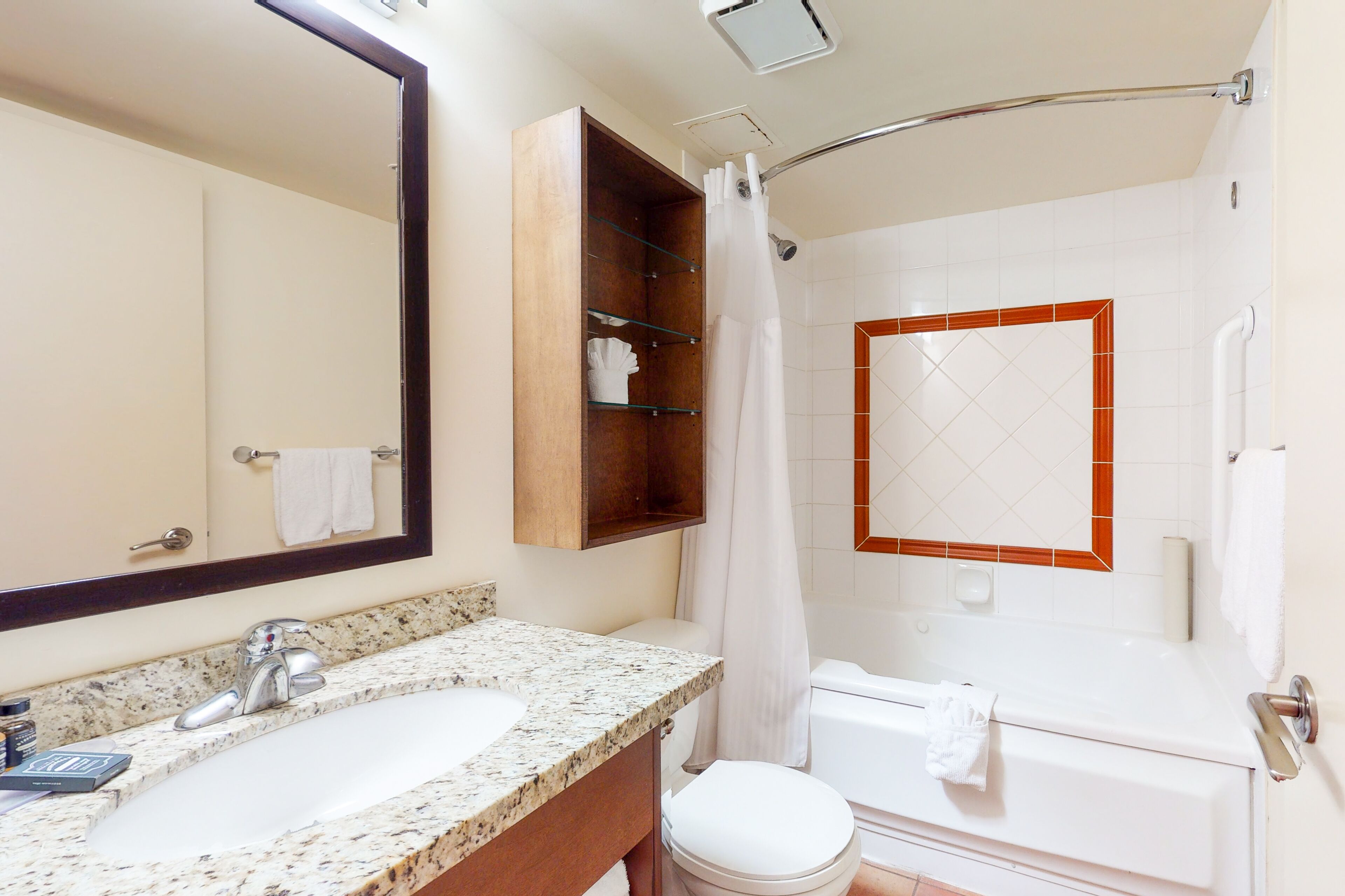 A bathroom with a sink, mirror, shower, and toilet.