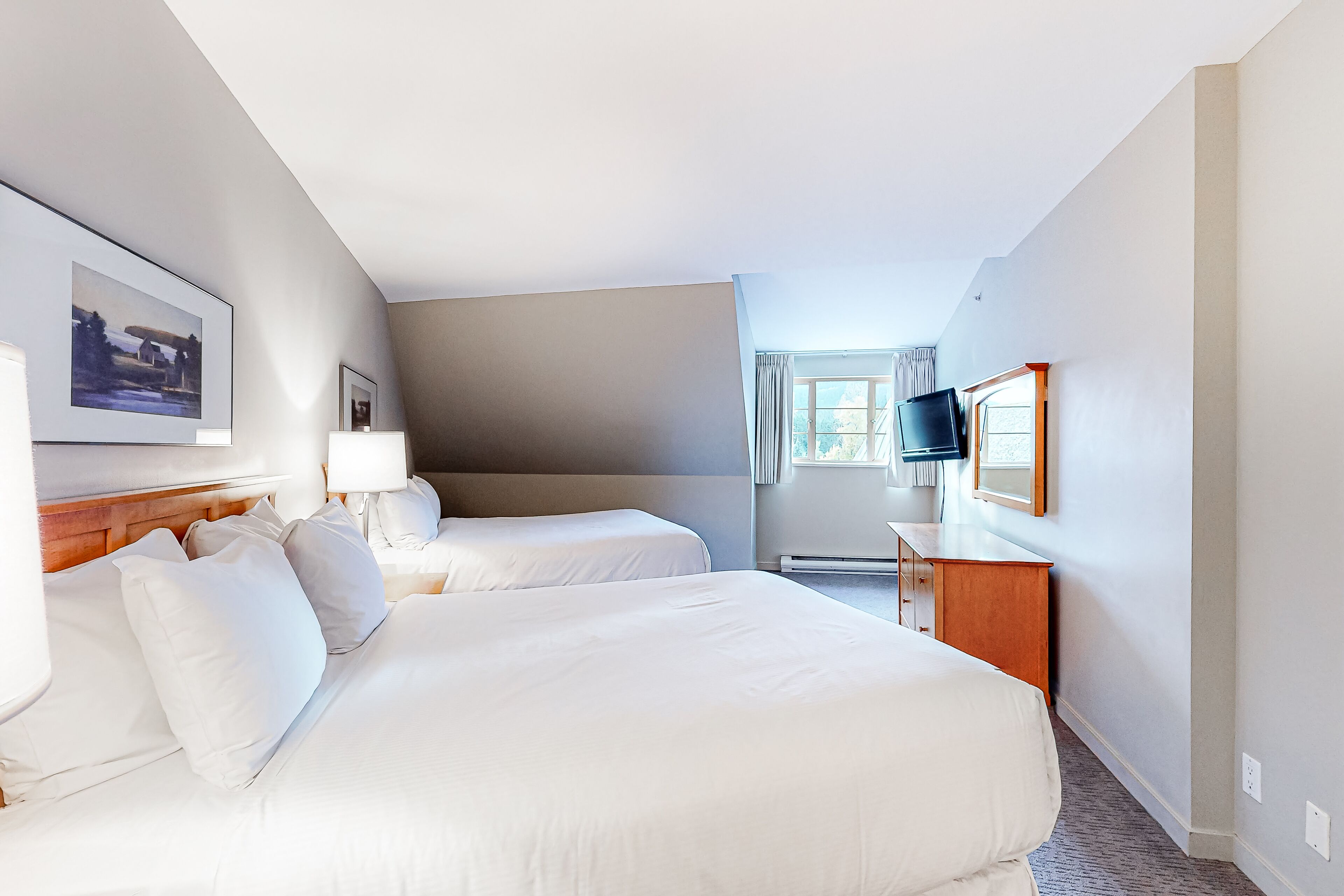 A hotel room with two beds, a flat-screen TV, a wooden dresser, and a window with curtains.
