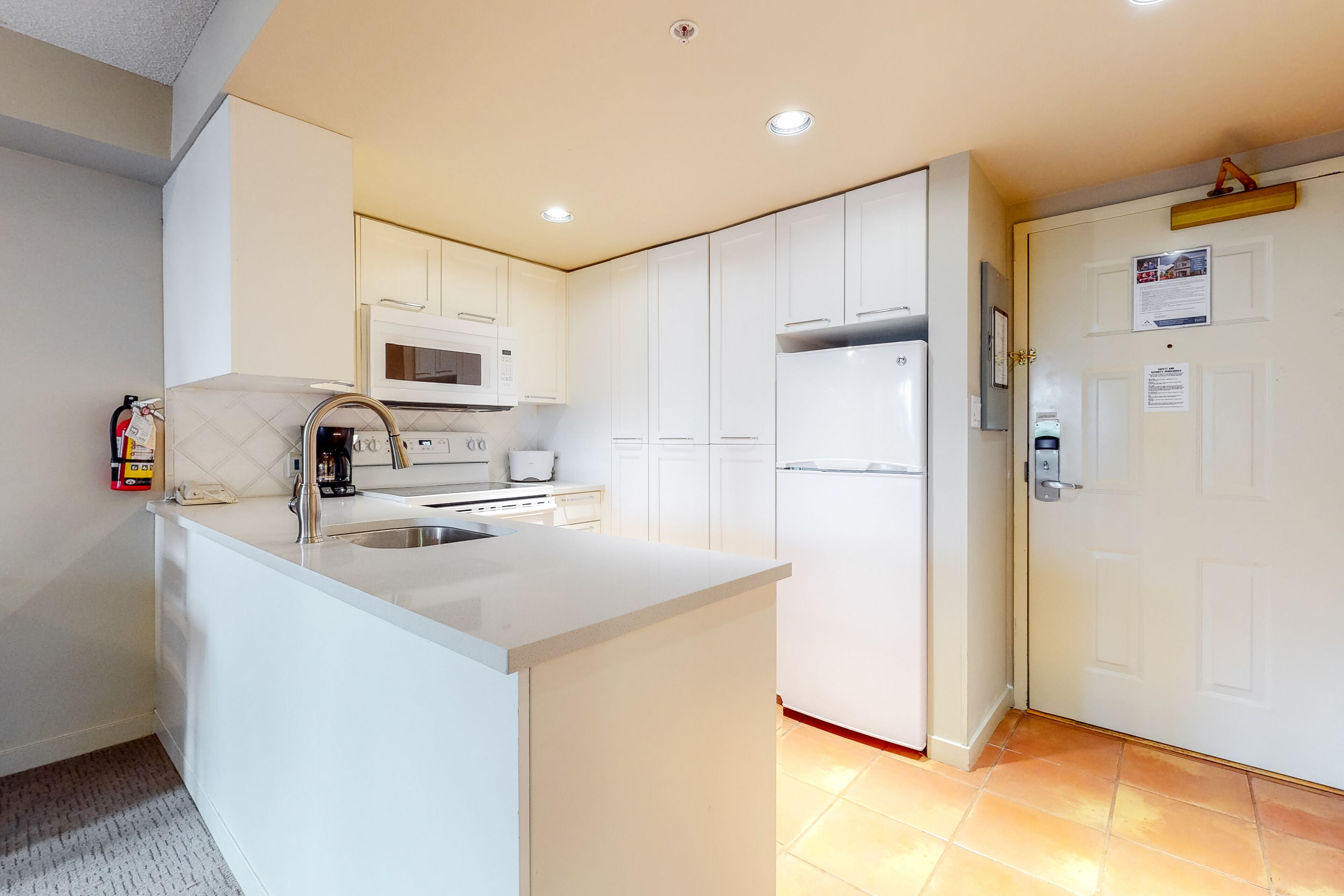 A modern kitchen with white cabinetry, a central island with a sink, and a stainless steel refrigerator.