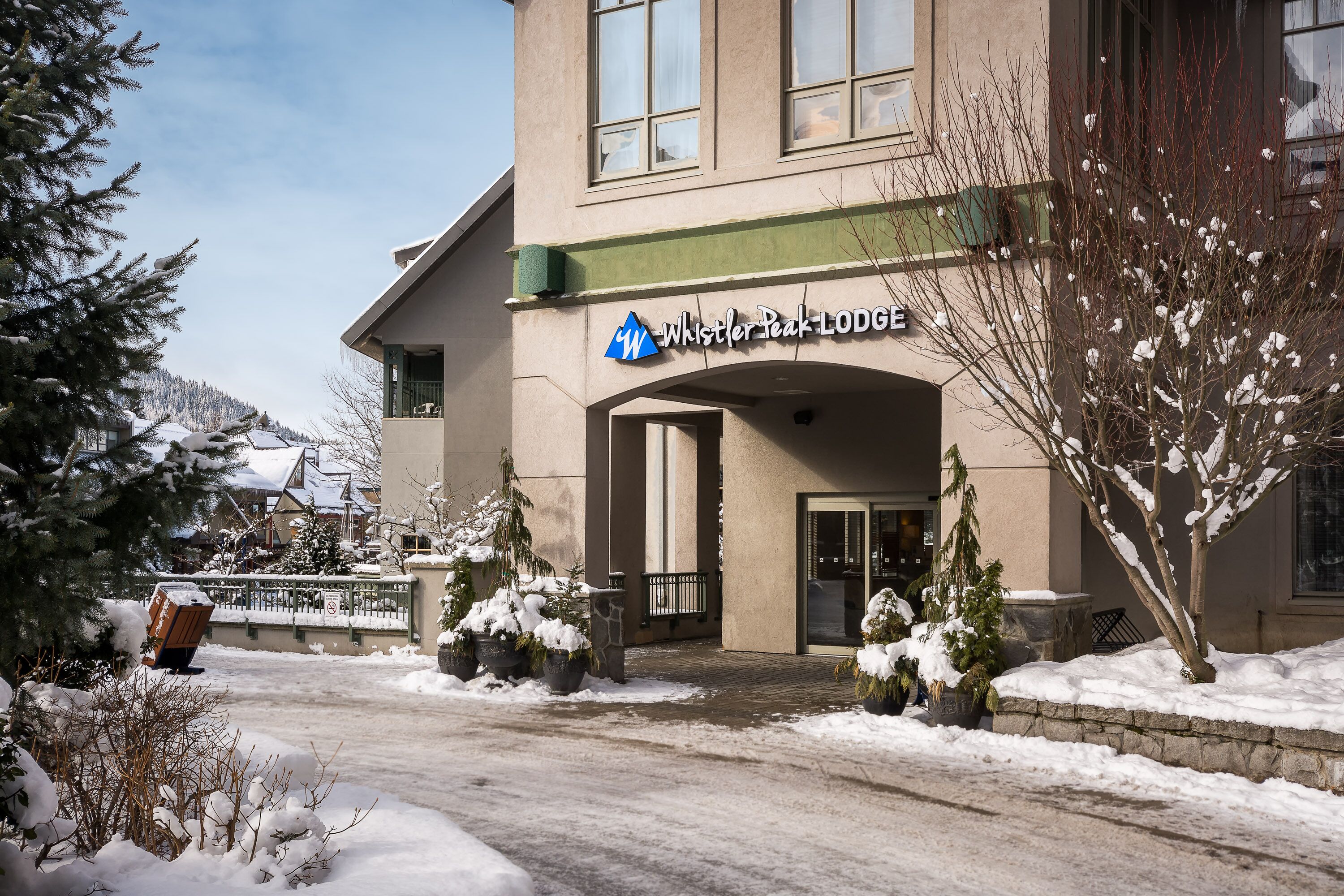Un edificio con un letrero que dice "Whistler Peak Lodge" y una entrada cubierta de nieve.
