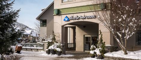 Un edificio con un letrero que dice "Whistler Peak Lodge" y una entrada cubierta de nieve.