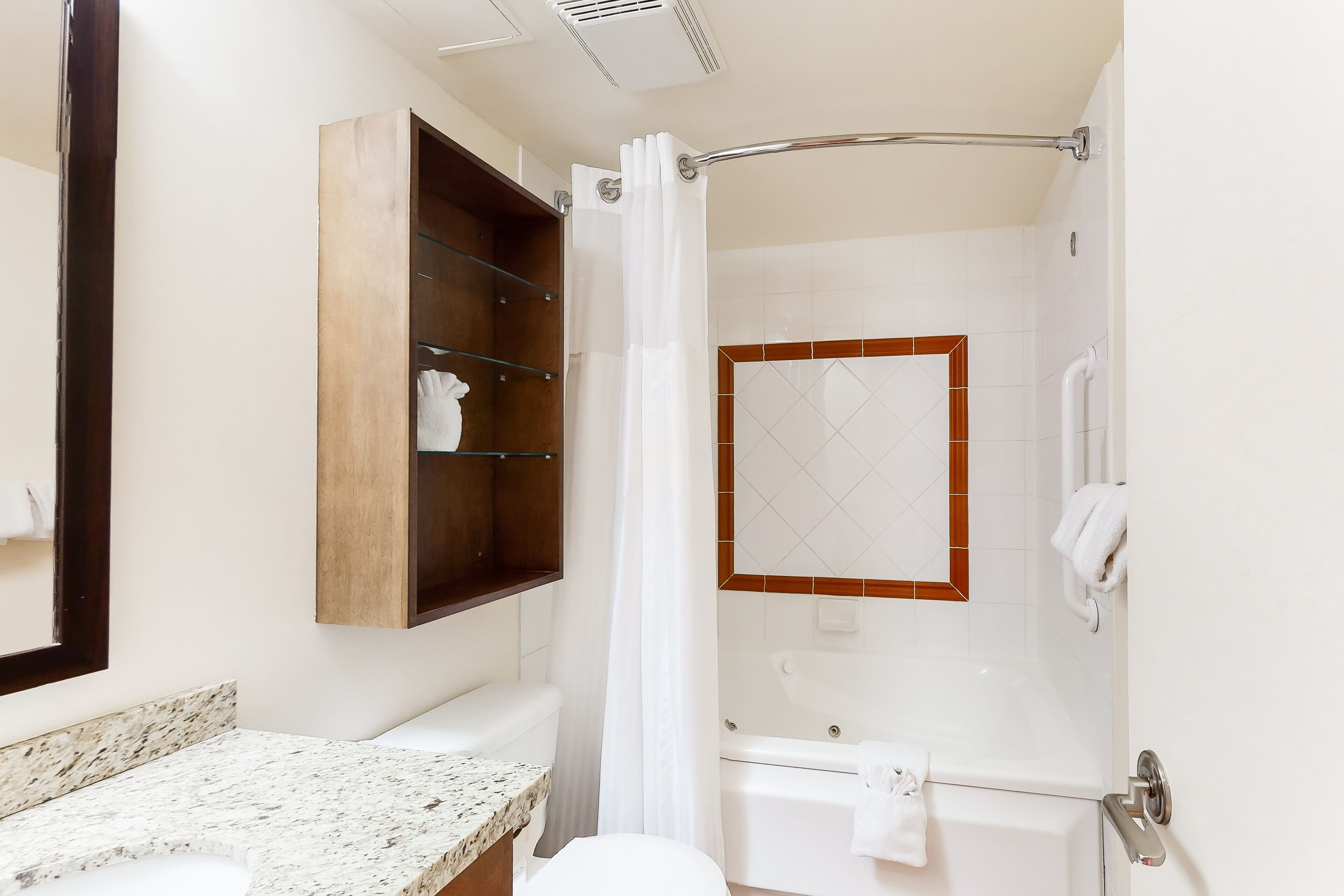 Une salle de bain avec un comptoir en marbre, des toilettes blanches, une baignoire et un rideau de douche.