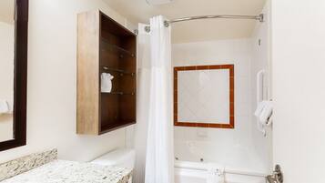 Une salle de bain avec un comptoir en marbre, des toilettes blanches, une baignoire et un rideau de douche.