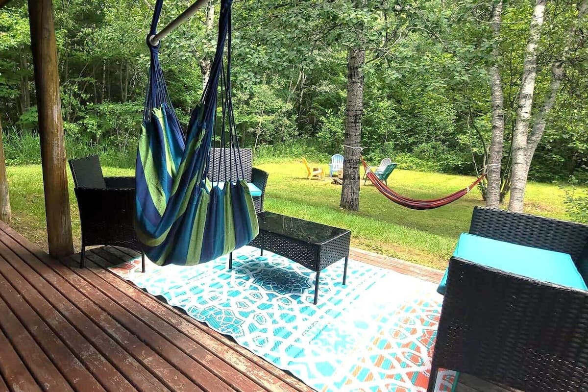 An outdoor deck with a wooden floor, a hammock, and outdoor furniture.