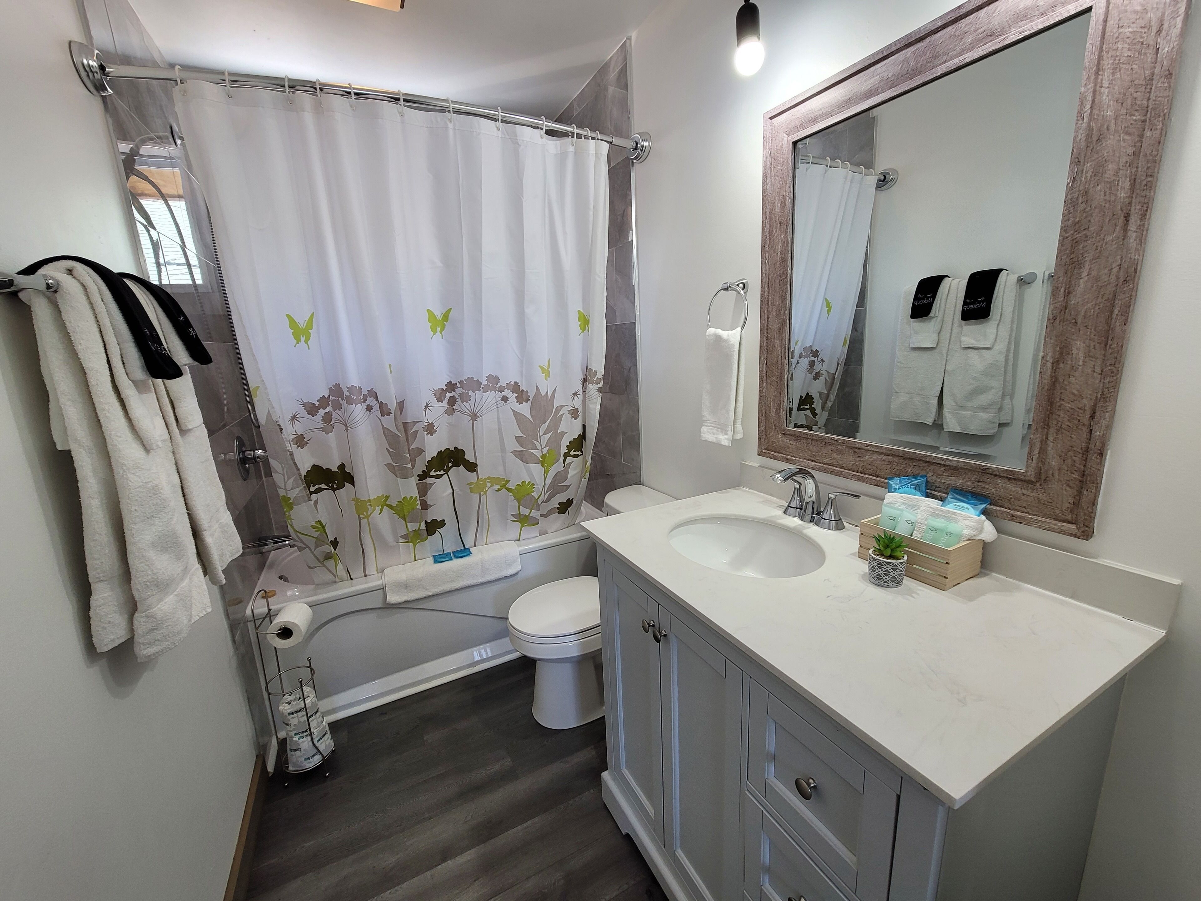 Ein Badezimmer mit Duschvorhang, Toilette, Waschbecken und Spiegel.