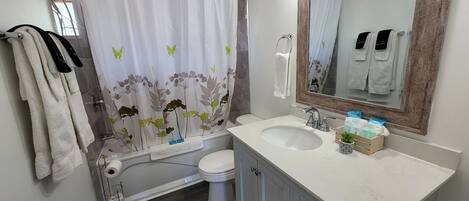 Ein Badezimmer mit Duschvorhang, Toilette, Waschbecken und Spiegel.