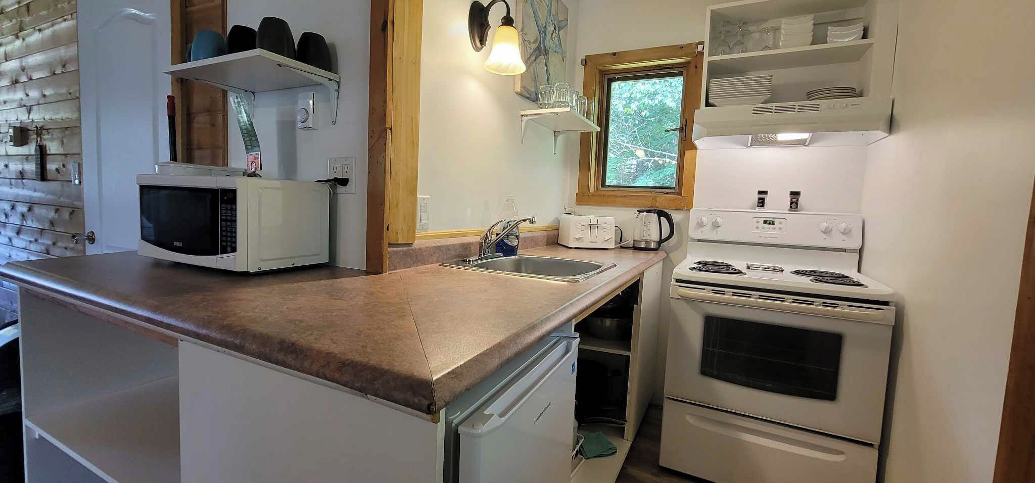 A compact kitchen with a microwave, toaster, sink, and stove.