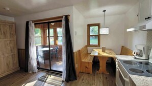 A compact kitchen with a wooden cabinet, a dining table, a window, and a stove. - Kouch Chalets (Saint Louis de Kent)