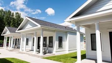 A row of white single-story houses with a covered porch and a clear blue sky.