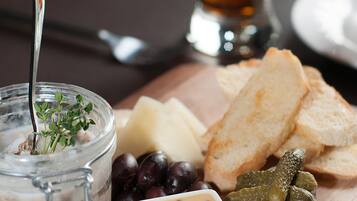 A charcuterie board with cheese, olives, pickles, and bread on a wooden board.
