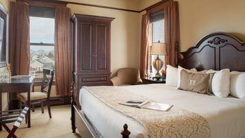 A hotel room with a large bed, a desk with a chair, a wardrobe, and a view of the outside.