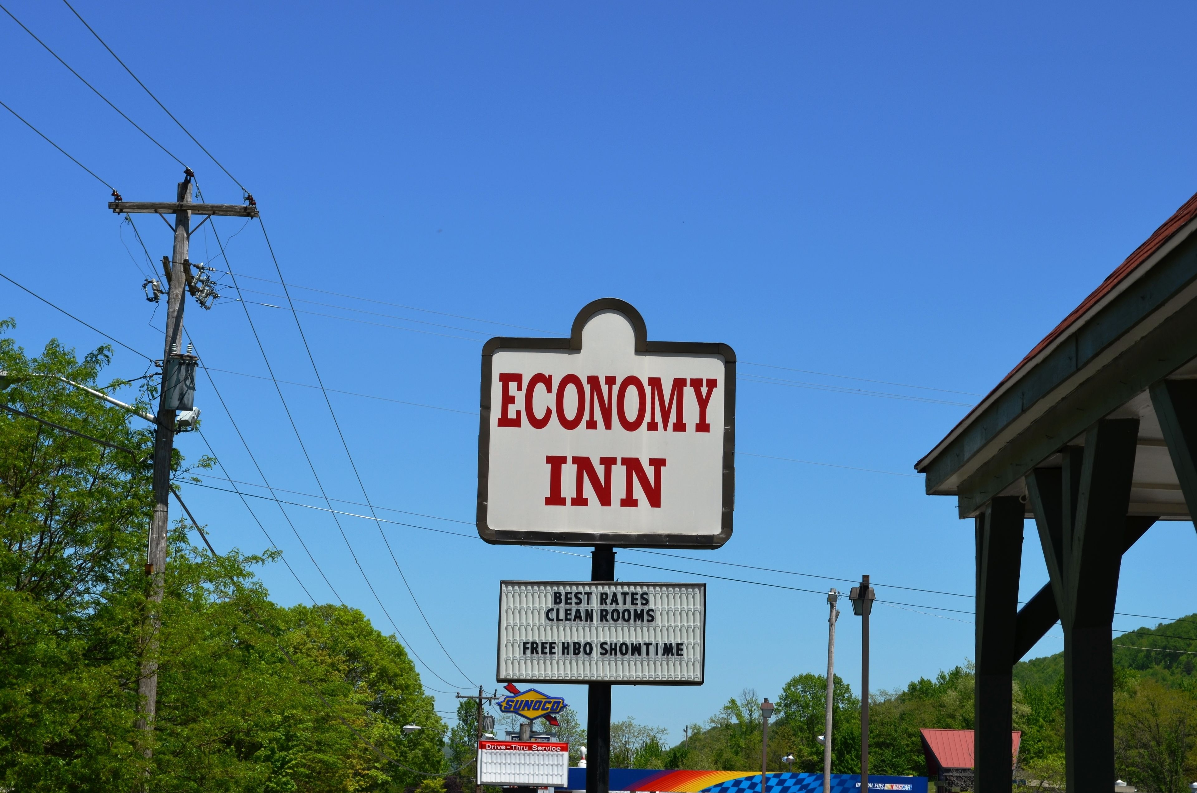 A sign for an Economy Inn with a clear view of the surrounding area, including power lines and a building in the background.