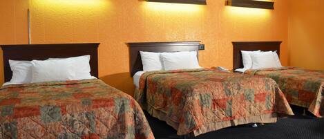 Une chambre d’hôtel avec deux lits, chacun doté d’une tête de lit en bois, d’oreillers blancs et d’une couvre-lit à motifs floraux.