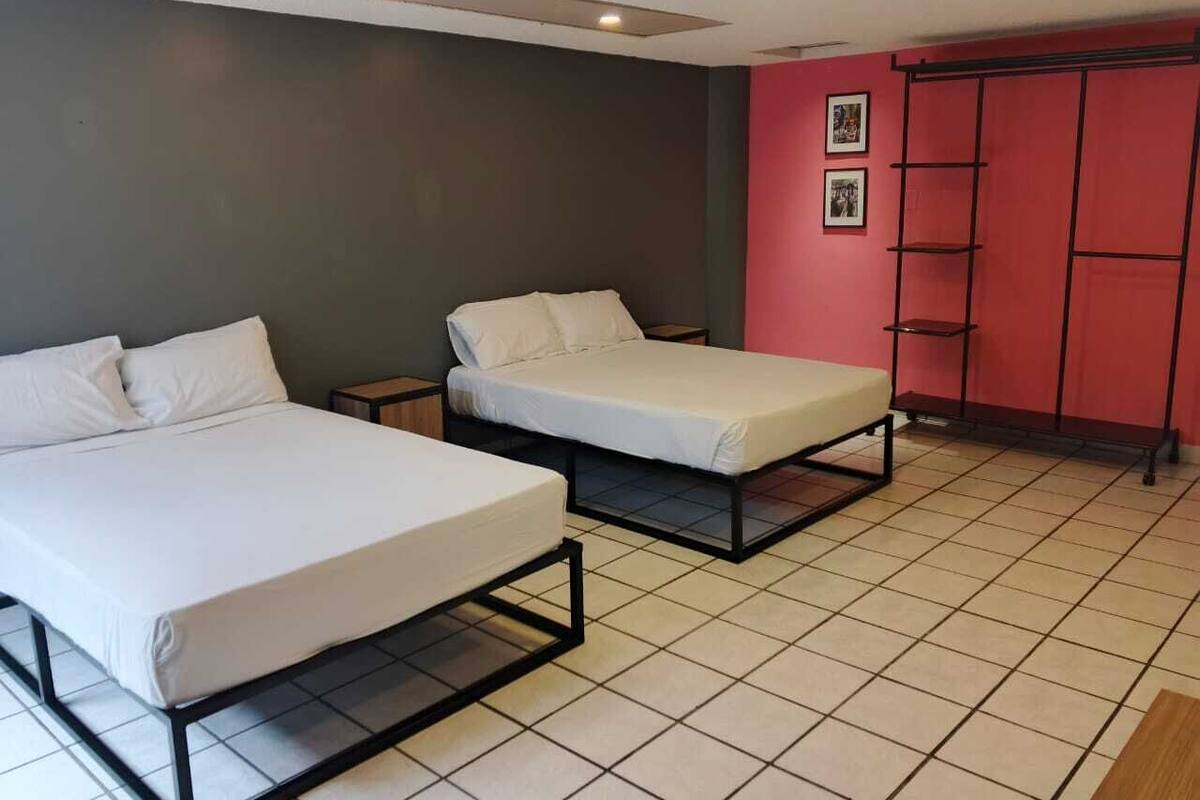 Una habitación con dos camas, un armario rojo y piso de baldosas.