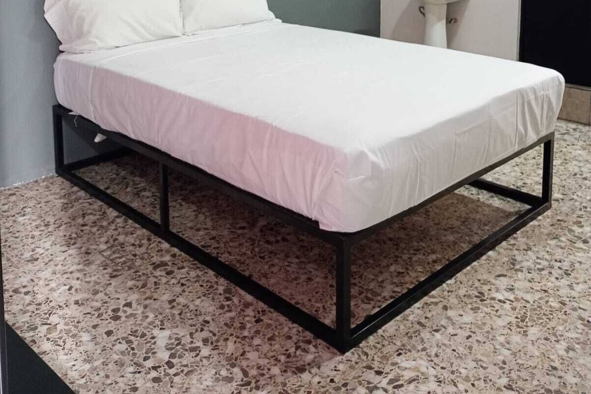 Un dormitorio con cama, lavamanos y espejo.