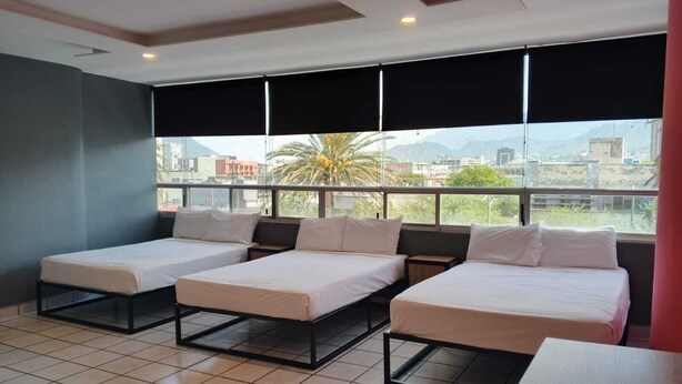 A hotel room with three beds, large windows, and a city view. - Unidades Privadas con AC-TV-WiFi y Estacionamiento en Centro de MTY (Monterrey)