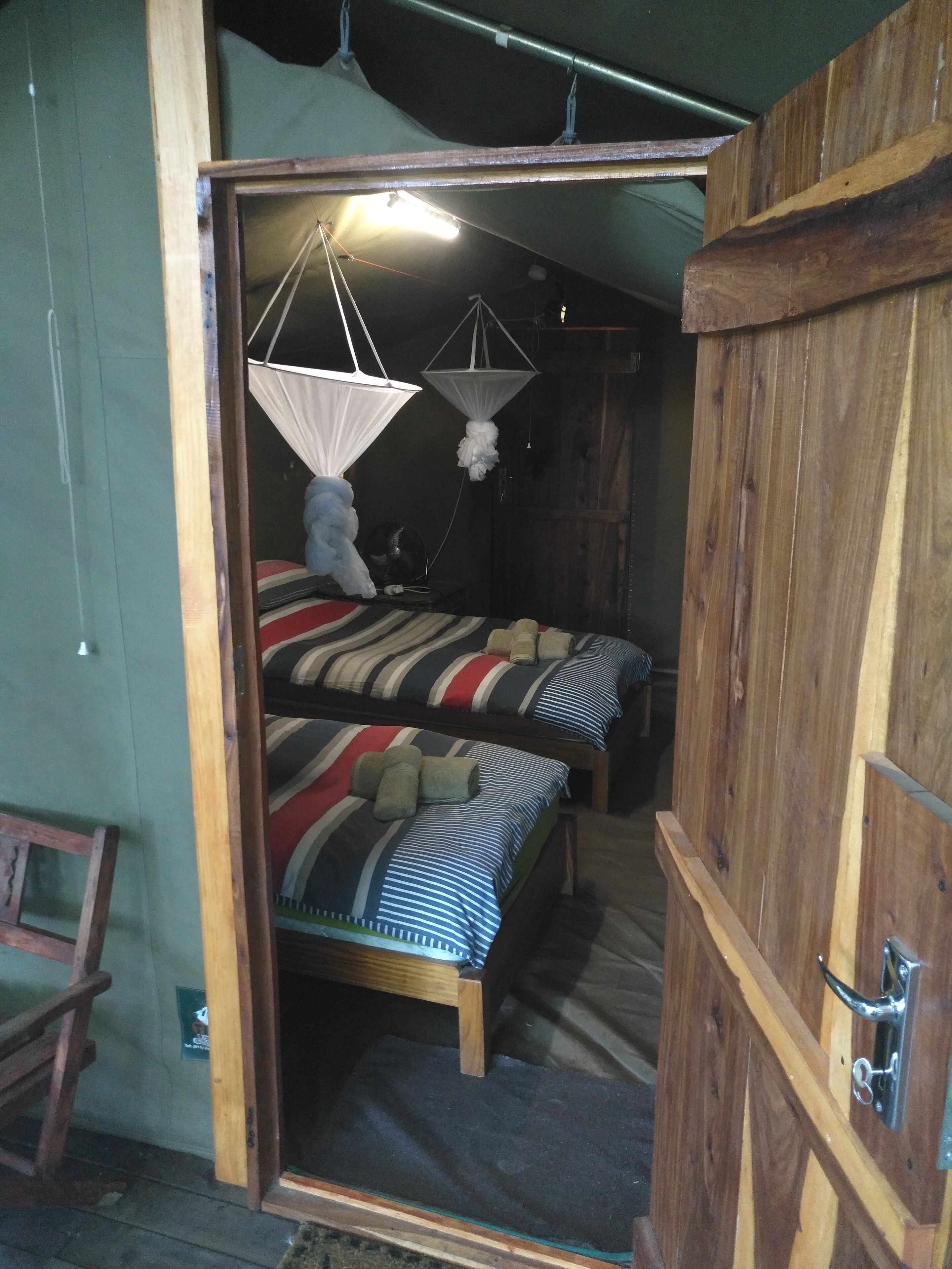 A room with two bunk beds, a wooden wardrobe, and a mosquito net over the beds.