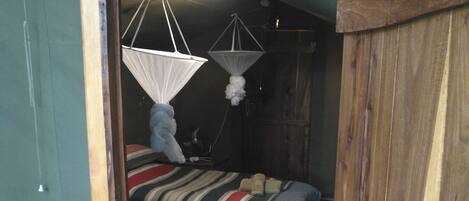 A room with two bunk beds, a wooden wardrobe, and a mosquito net over the beds.