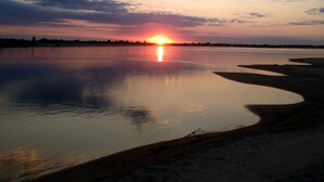 A sunset over a calm body of water with a shoreline.