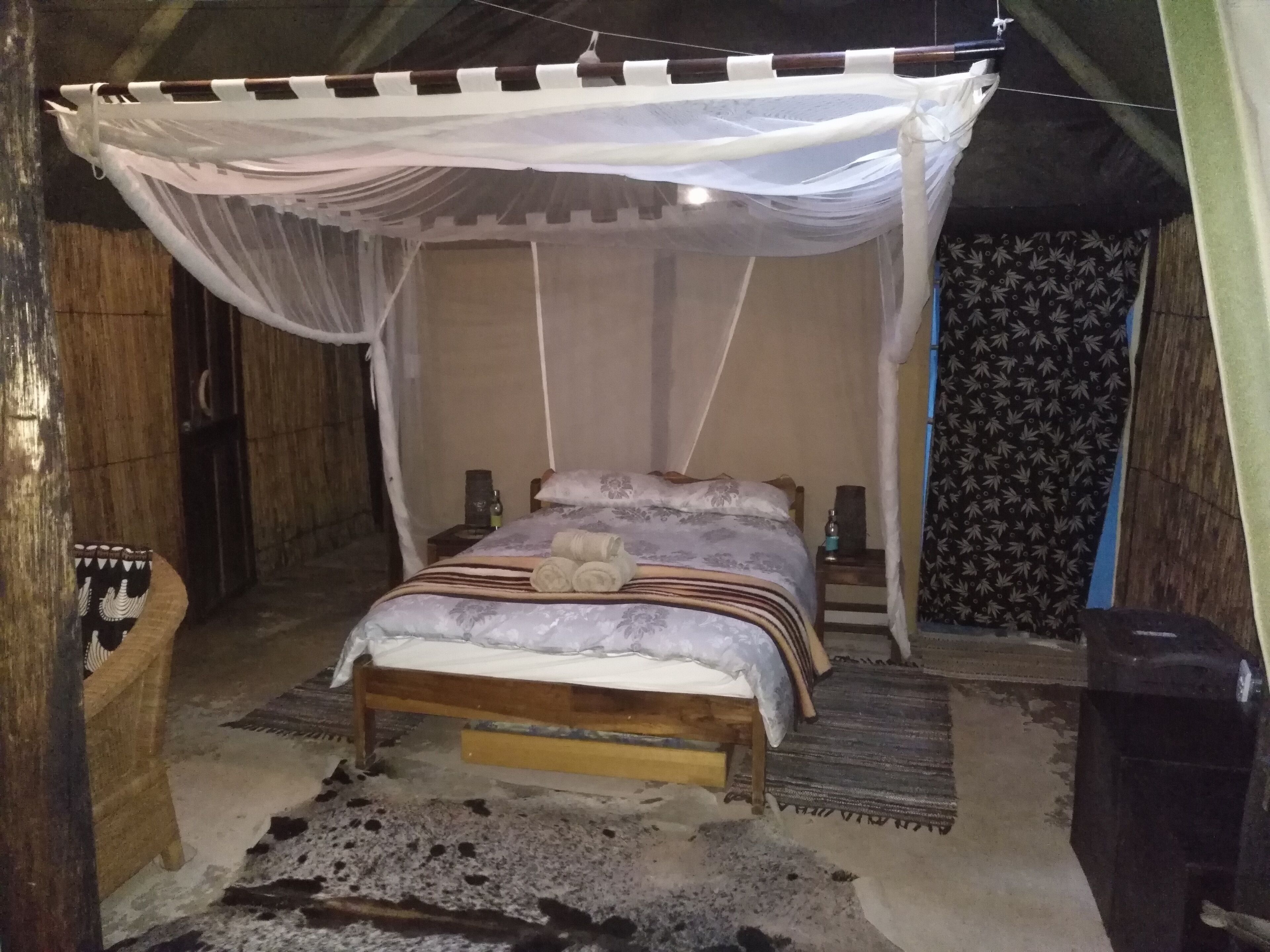 A single bed with a canopy, a bedside table, a small rug, and a cowhide rug on the floor.