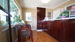 A kitchen with wooden cabinets, a window with blinds, and a counter with a potted plant. - Redwood Inn (Santa Rosa)