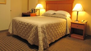 A hotel room with a large bed, two bedside lamps, a nightstand with a phone, and a door. - Redwood Inn (Santa Rosa)