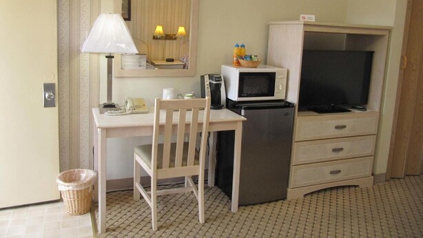 A compact kitchenette with a microwave, refrigerator, and a small table with a chair. - Redwood Inn (Santa Rosa)