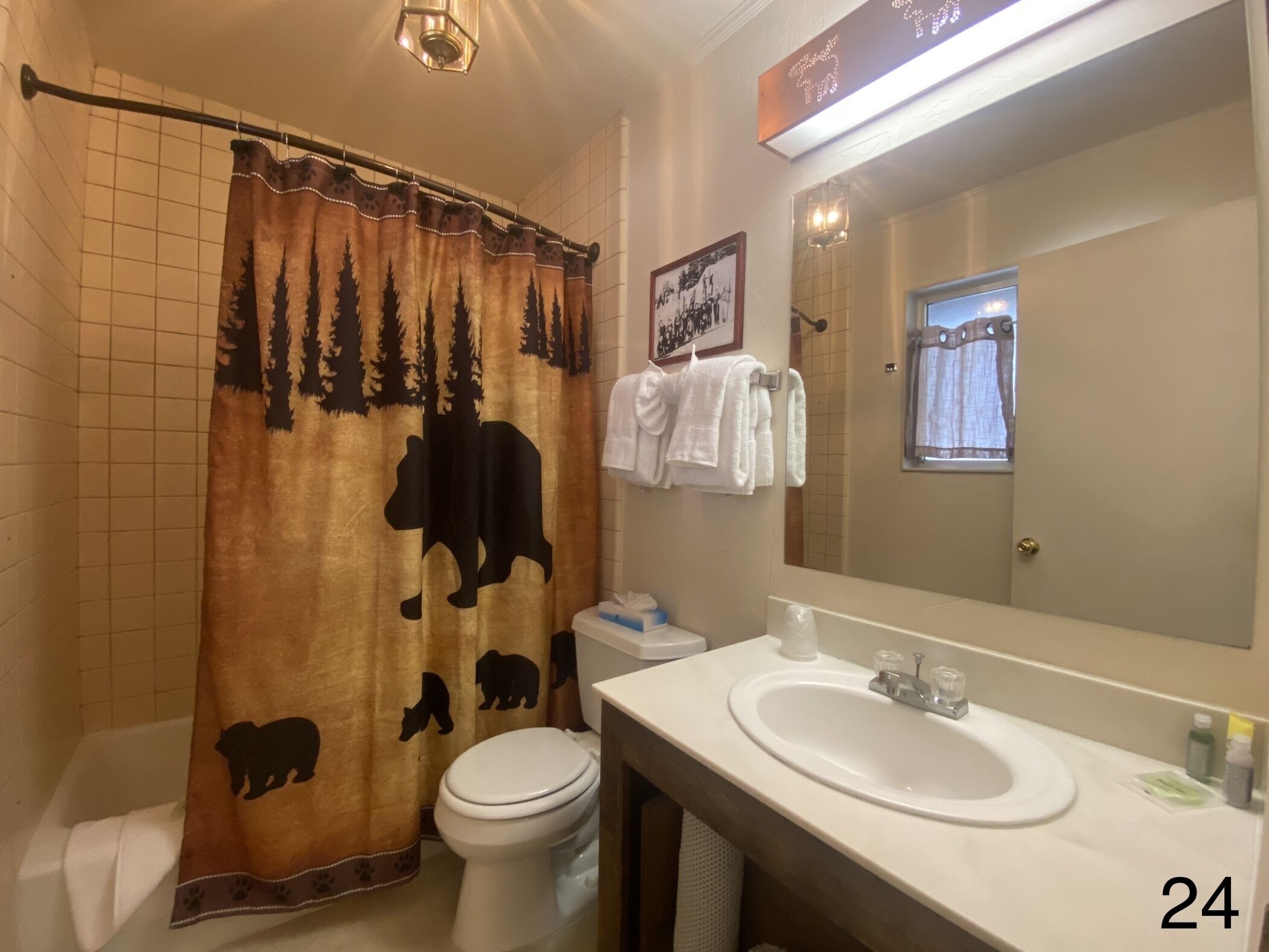 A bathroom with a shower curtain featuring a bear design, a toilet, a sink, and a mirror.