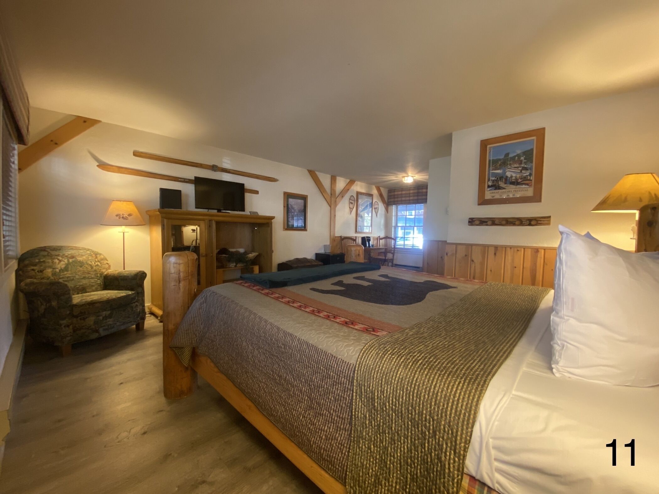 A cozy bedroom with a large bed, a chair, a desk, and a television.