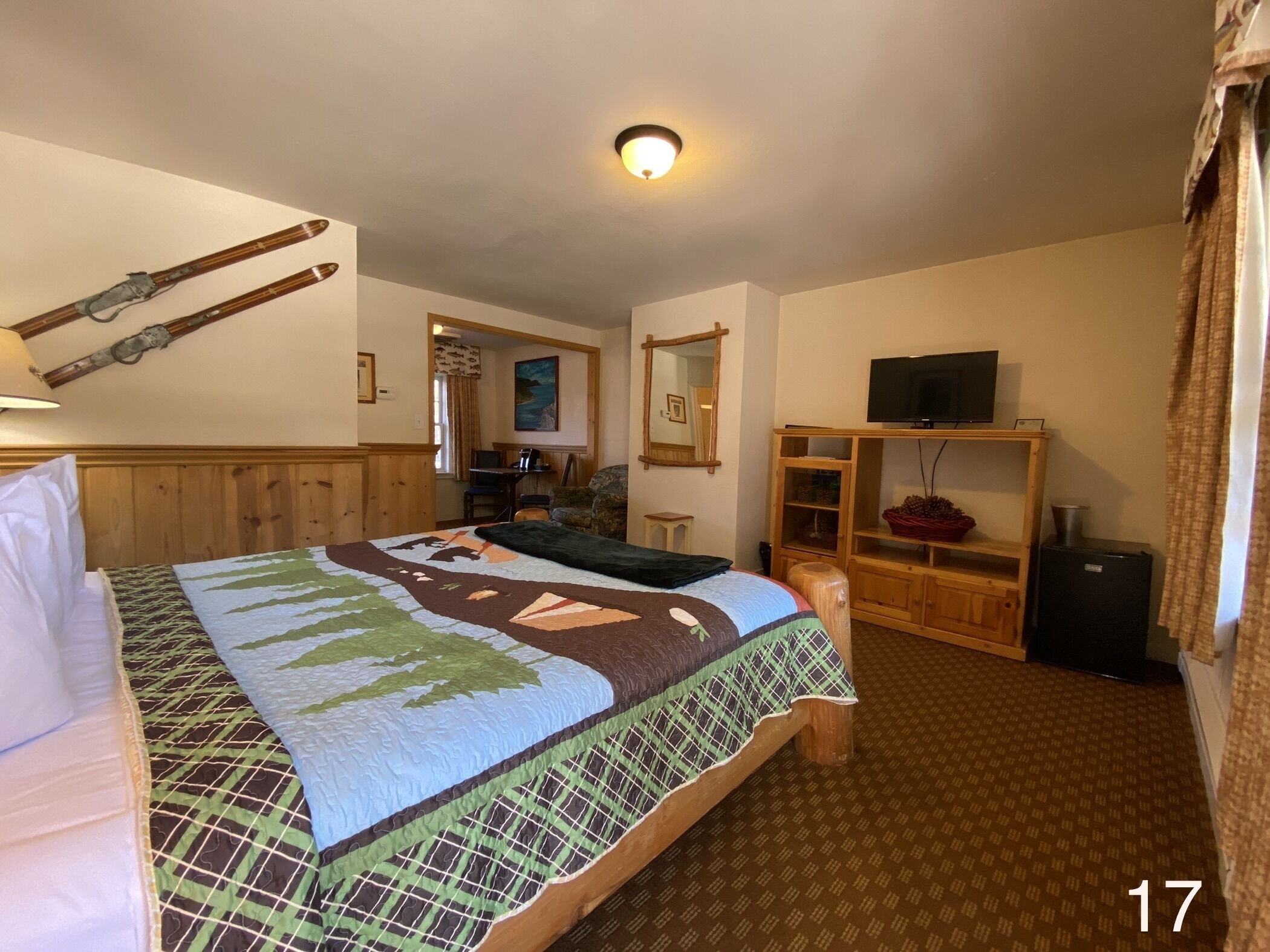 A hotel room with a bed, a television, a desk with a computer, and a mirror.