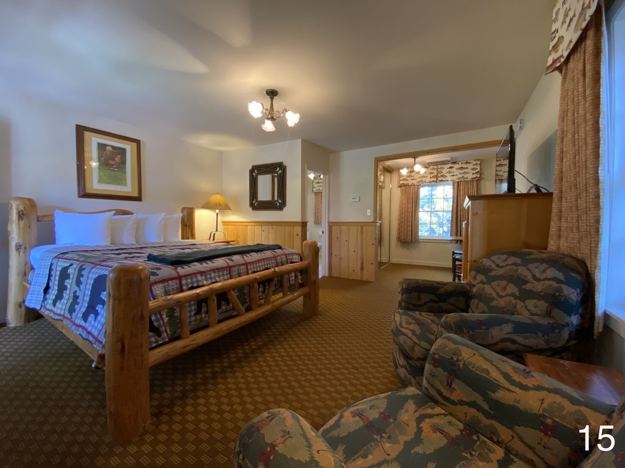 A bedroom with a bed, a chair, a lamp, a mirror, and a window.