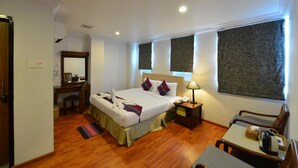 A hotel room with a large bed, bedside table, lamp, and a small table with chairs. - Hotel K Yangon (Yangon)