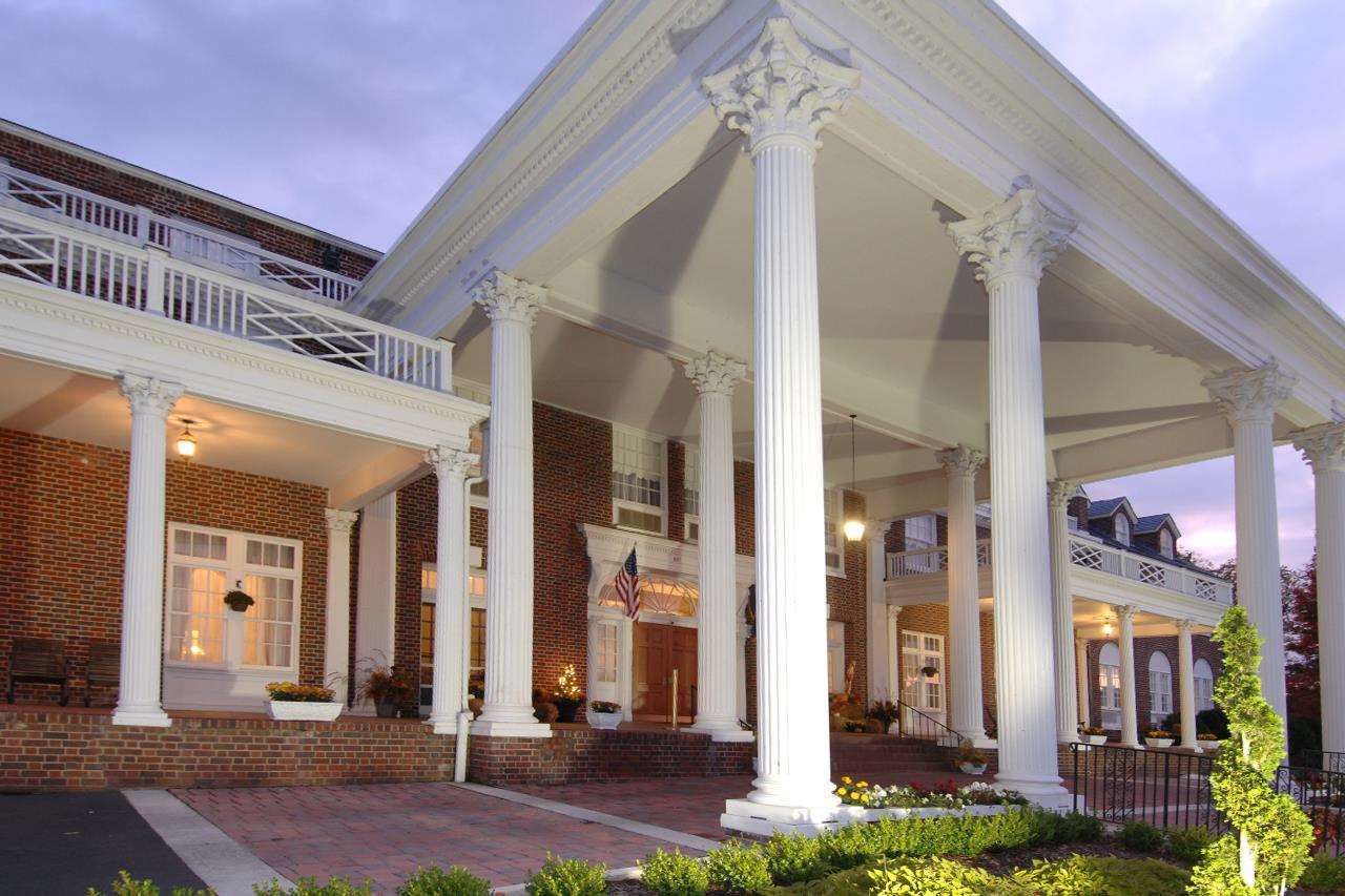 A brick building with white columns and a balcony.