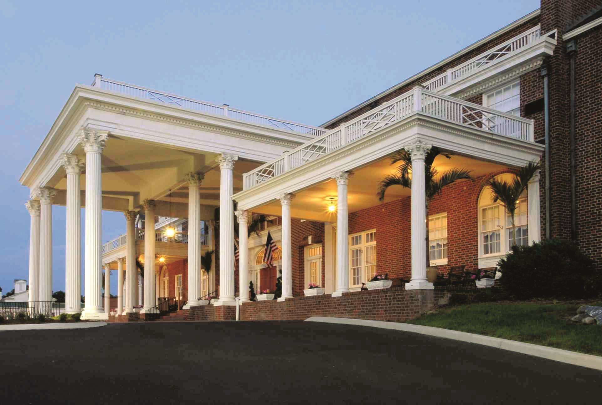 A large building with a covered entrance, columns, and a balcony.