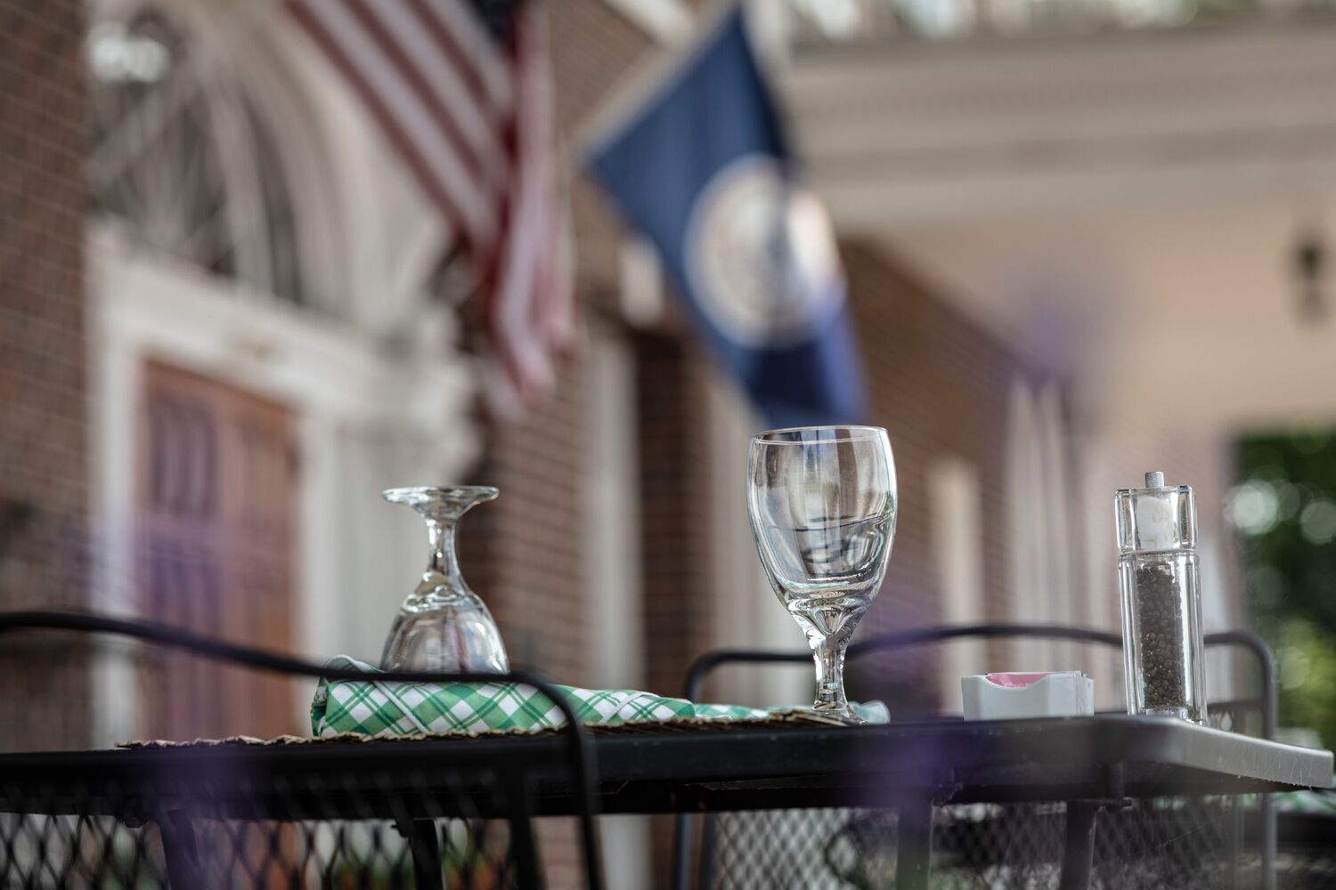 A table with a glass, a salt shaker, and a pepper shaker.