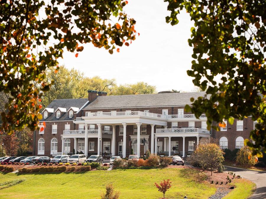 A large brick building with a central courtyard, multiple balconies, and a parking area.