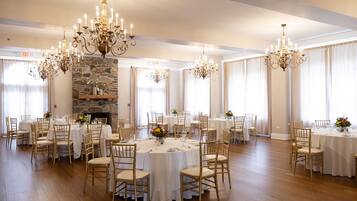 Une vaste salle à manger avec des tables rondes, des chaises dorées et des lustres.