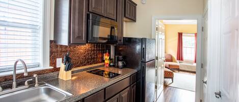 A modern kitchen with dark wood cabinets, a stainless steel sink, and a black refrigerator.